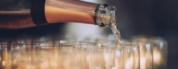 A bottle of champagne is being poured into glasses.