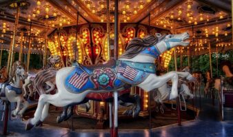 A brightly lit carousel at Six Flags, adorned with intricately decorated horses, offers a great escape with its vivid colors and illuminated lights in the background.