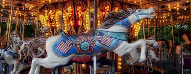 A brightly lit carousel at Six Flags, adorned with intricately decorated horses, offers a great escape with its vivid colors and illuminated lights in the background.