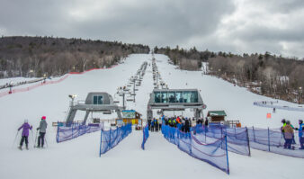 Skiers at West Mountain eagerly await their turn in line at the snowy ski resort, ready to board the lift and embrace the slopes.