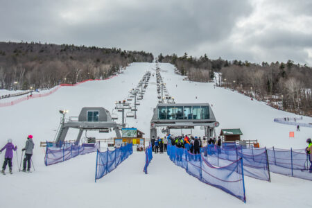 Skiers at West Mountain eagerly await their turn in line at the snowy ski resort, ready to board the lift and embrace the slopes.