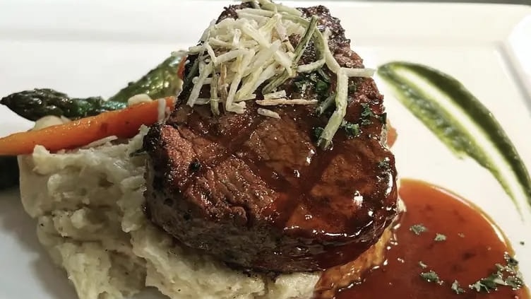 High-end steak dish with mashed potatoes and sauce.